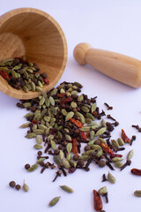 Scattered spices from the wooden mortar on the white table