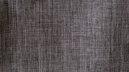 Close up of woven gray-brown fabric with tight grid texture, ideal for textile, fashion, and material design themes