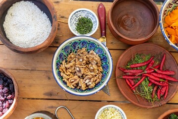 A vibrant assortment of ingredients for traditional cuisine including rice, walnuts, herbs, spices and chili peppers in ceramic bowls