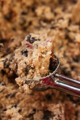 Close up of raw müsli oatmeal raisin cookie dough made of flour, rolled oats, sugar, eggs, raisins, muesli and dried fruit in stainless steel cookie scoop