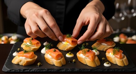 A chef carefully arranges smoked salmon canapés on a slate platter, garnishing them with fresh dill.