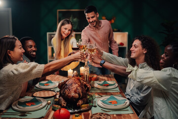 Friends toasting during thanksgiving dinner with roasted turkey