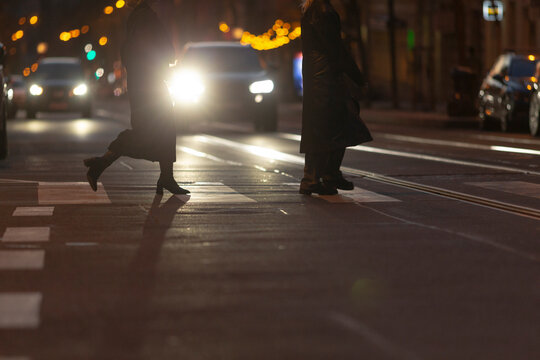 In the bustling cityscape at night, pedestrians navigate a busy street while vehicles approach, emphasizing the critical importance of urban traffic awareness alongside nighttime safety