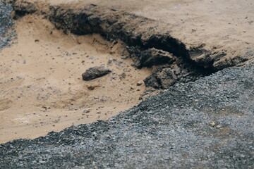 Close-up of crushed stone and gravel next to an eroded ditch in sandy soil. Groundwork at a construction site.