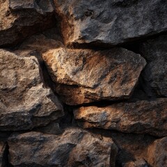 Close-up view of a rough stone wall, unevenly sized rocks, varying shades of gray and brown. Sunlight highlights some areas
