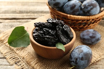 Dried prunes and fresh plums on wooden table, closeup