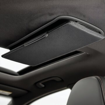 Close up of a modern car s open panoramic sunroof with a textured black interior headliner and frame