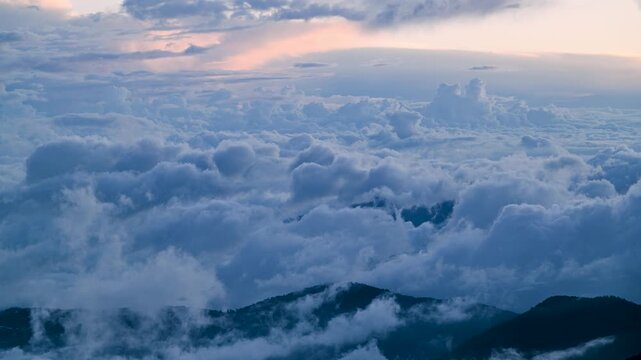 Aerial view of Hehuanshan, Renai, Nantou, Taiwan. Early autumn sun lights a winding mountain road above a sea of clouds and green slopes.