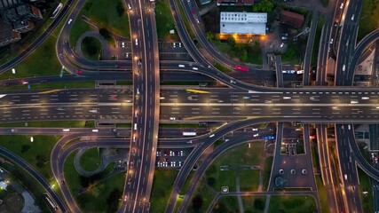Aerial view of a highway interchange at night with illuminated traffic and urban structures. - Powered by Adobe