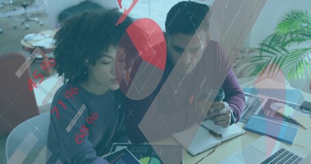 Reviewing two office professionals analyzing financial data on tablet and notebook at wooden table