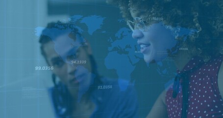 Analyzing laptop data two colleagues wearing red blouse, eyeglasses at desk with world map overlay