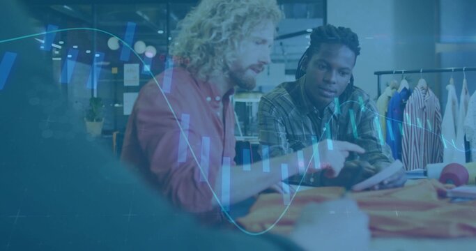 Two male designers collaborating over fabric swatches in fashion design studio, with coffee mug