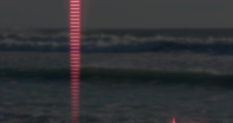 Shining narrow vertical red beam reflecting off ocean waves at seaside at night, faint horizon line