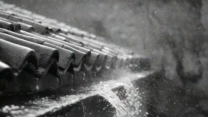 Heavy rain cascading down a dark gray tiled roof