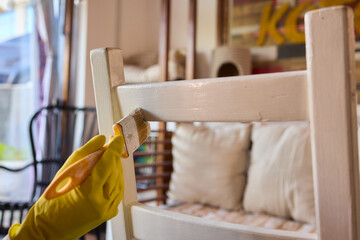 Engage in DIY chair restoration using a paint brush and protective gloves for the process