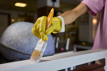 Engage in DIY chair restoration using a paint brush and protective gloves for the process