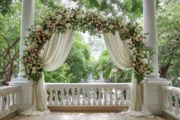 Floral archway on a veranda, draped with sheer white fabric, overlooking lush greenery