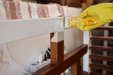 Engage in DIY chair restoration using a paint brush and protective gloves for the process