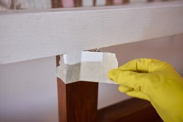 Engage in DIY chair restoration using a paint brush and protective gloves for the process
