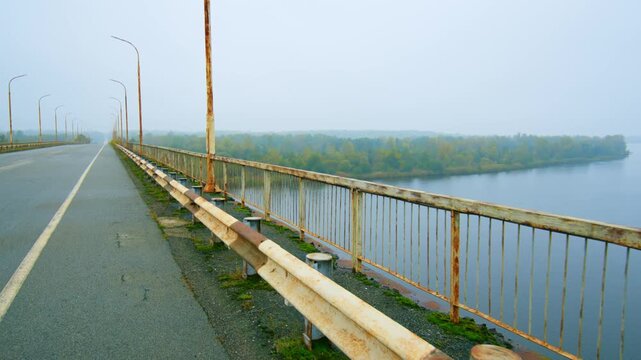 The Paryshivskyi Bridge spanning the Pripyat River, shrouded in a misty, atmospheric autumn fog. The scene captures the serene and somewhat haunting beauty of the Polesia region, with the river flowin