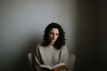 thoughtful woman sits in armchair deeply engaged in reading selfdevelopment book her face reflecting inspiration