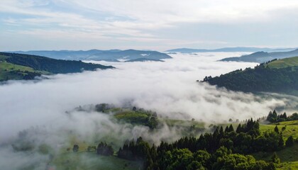 Aerial View of Verdant Mountain Valleys Enshrouded in Soft White Clouds Under Pale Blue Sky at Daytime