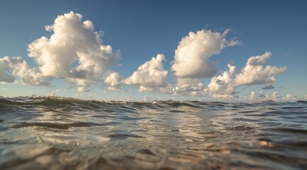 Low angle view of ocean waves meeting a vibrant sky full of puffy clouds