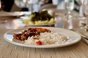 Plate of white rice and meat on a table, a staple food in cuisine