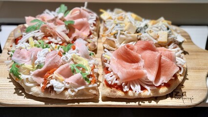 Top view of delicious sliced pizza with cheese, sausage, ham, bacon, greens, mayonnaise on wooden dish on the table at the restaurant