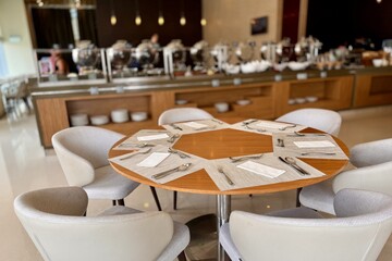 A neatly arranged around table with armchairs, dining ware and condiments
