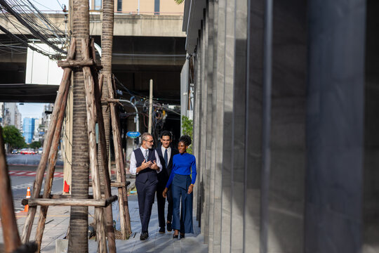 A multicultural group of business people including white and African professionals walking together in the city business district showcasing teamwork diversity and modern urban lifestyle