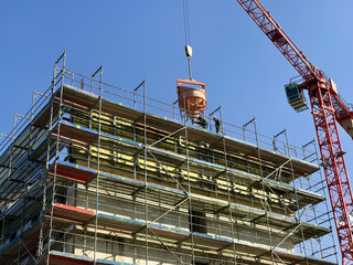 Naklejka premium A massive structure being built with scaffolding and a crane. Constructing building of a skyscraper in the urban landscape