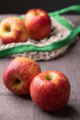 Red apple fruit (Envy apple) on brown fabric background with mesh bag
