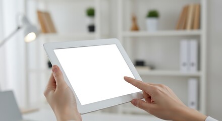 Hands holding a tablet with a blank screen in a bright office setting.