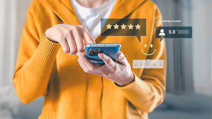 A person gives a five-star review on a smartphone, expressing satisfaction with a service by...