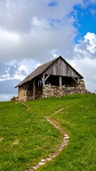Obraz premium Wooden mountain hut on grassy hill