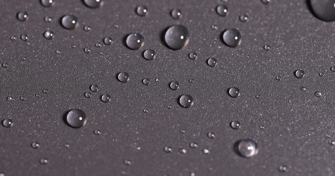 black plastic surface covered with water drops, details of the wet part of an object made of black plastic
