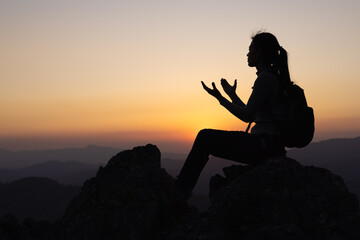  Christian catholic woman are praying to god. Christ religion and christianity worship or pray concept. Praying hands on a background of rising sun. Person believes and has faith in Jesus Christ.