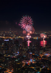 Vibrant fireworks illuminate a glittering cityscape at night, celebrating a joyous occasion over the water.