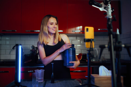 Influencer Holding A Jar Of Protein Promoting It To The Camera. Charismatic fitness woman endorsing dietary supplements 