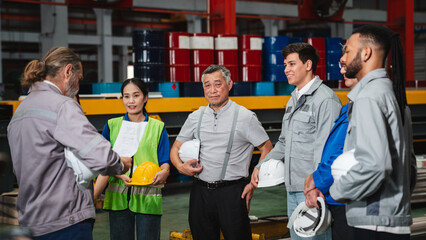 Team engineers and foreman gather for a meeting at the factory machines. Industry workers join together for collaboration and success.
