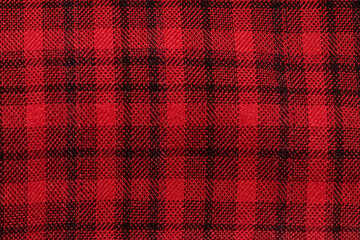 Classic red and black plaid cloth fabric close-up texture. Featuring a classic checkered pattern....