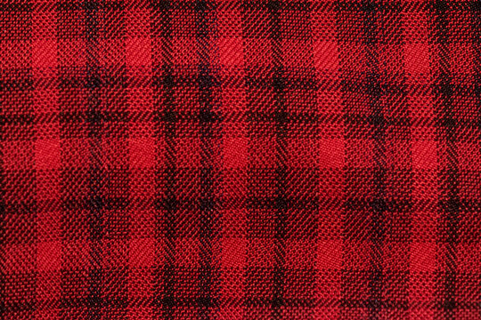Classic red and black plaid cloth fabric close-up texture. Featuring a classic checkered pattern. For textile sample and background. Flannel shirts and rustic fashion - Powered by Adobe