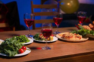 A cozy dinner table set with vibrant dishes, red wine glasses, and warm lighting, symbolizing togetherness, comfort, and the joy of sharing delicious food in a relaxed, festive atmosphere, no people.
