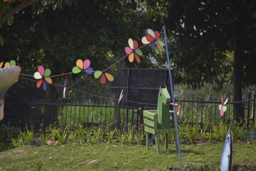 Flower Spinner. Colorful pinwheel in the wind at Garden. Rainbow colored spinner.  Windmill in garden. Simple kinetic environment decor. 