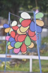 Flower Spinner. Colorful pinwheel in the wind at Garden. Rainbow colored spinner.  Windmill in garden. Simple kinetic environment decor. 