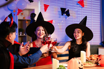 Friends celebrate a lively Halloween party with costumes, pumpkin lanterns, wine, delicious food on the table. The night is filled with laughter, colorful lights, and festive energy for seasonal joy.
