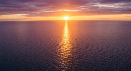Obraz premium Sunset over calm water creating a vibrant orange and purple sky