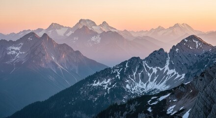 Mountain layers at dawn, some snowy, some forested, against a colorful sky