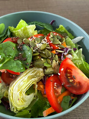 Fresh Garden Salad With Assorted Vegetables, Seeds, and Dressing Served in a Blue Bowl on a Wooden Table